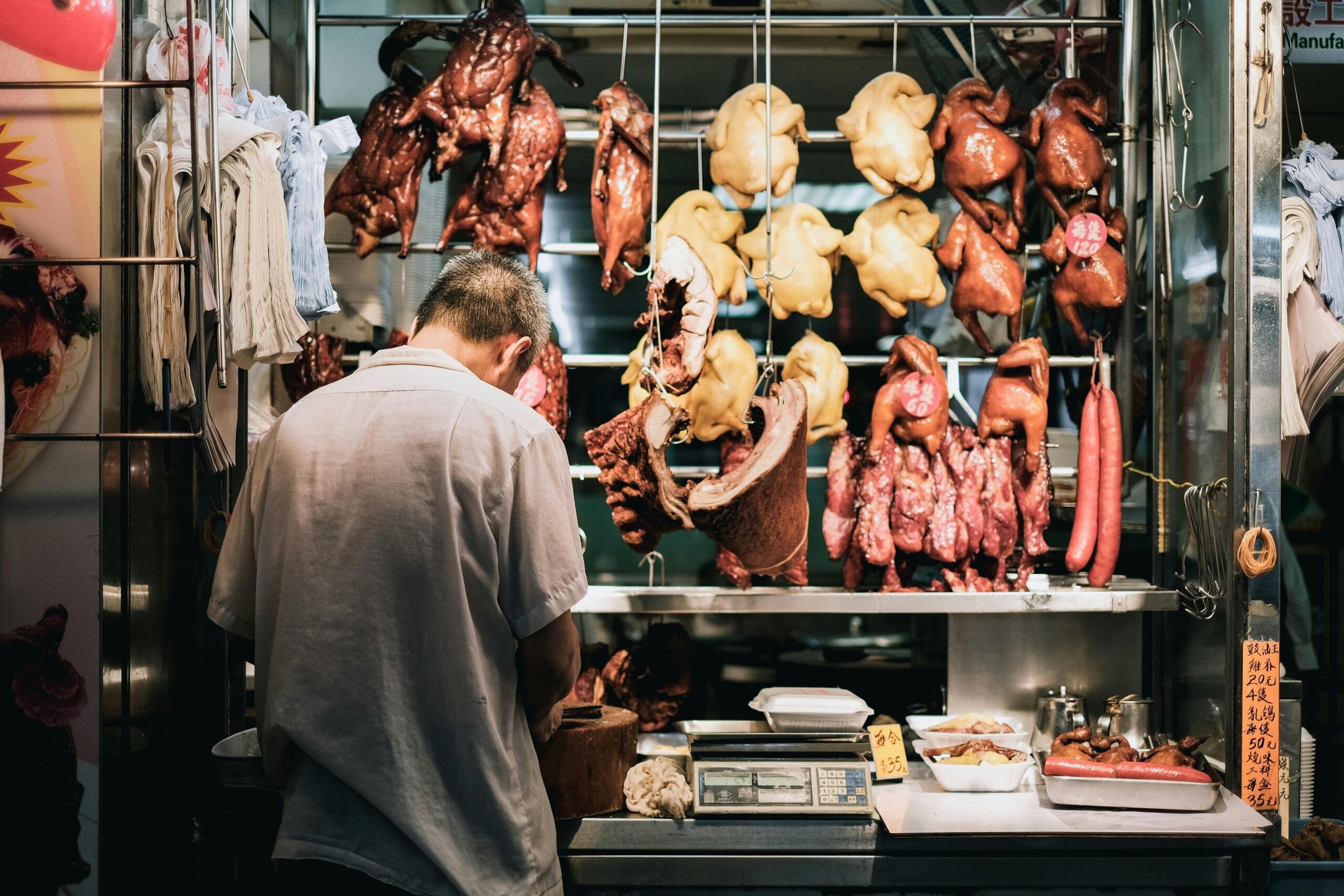 Back view of a butcher preparing meat in a Hong Kong wet market stall.